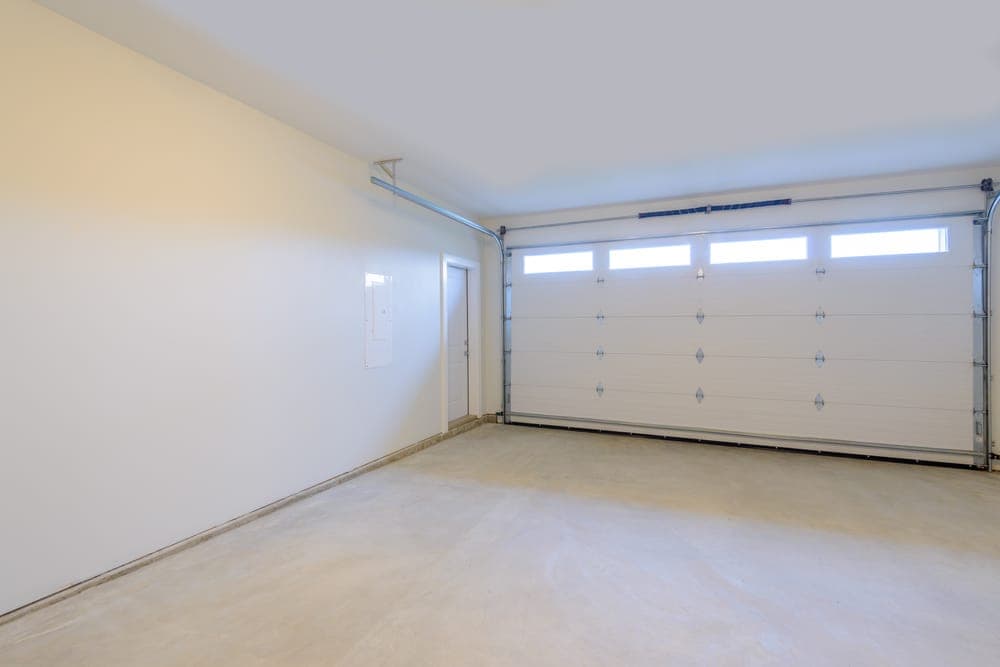 Empty garage with an overhead door and windows